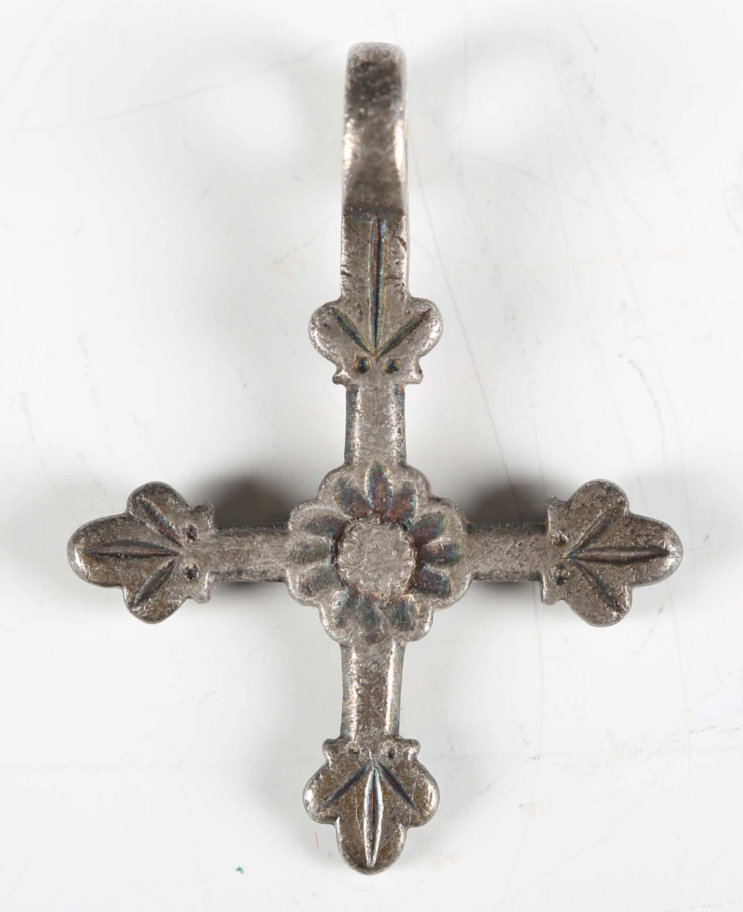 A medieval white metal cross pendant with central flowerhead and suspension
