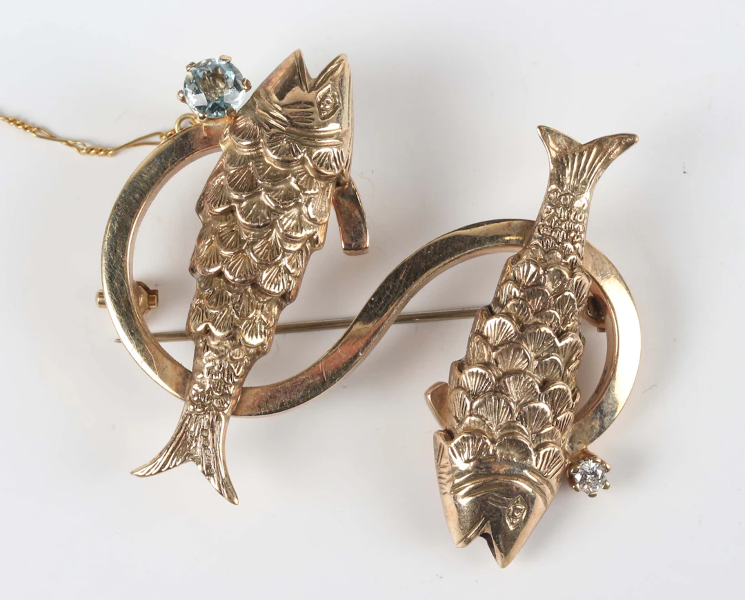 A gold brooch, designed as the letter ‘S’ with two fish motifs, mounted