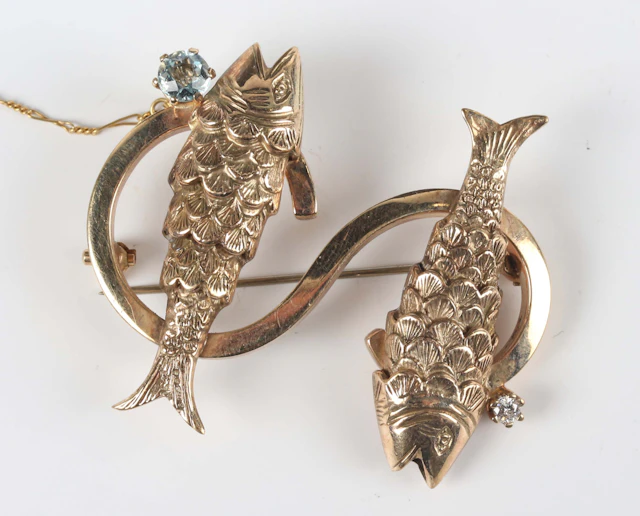 A gold brooch, designed as the letter ‘S’ with two fish motifs, mounted