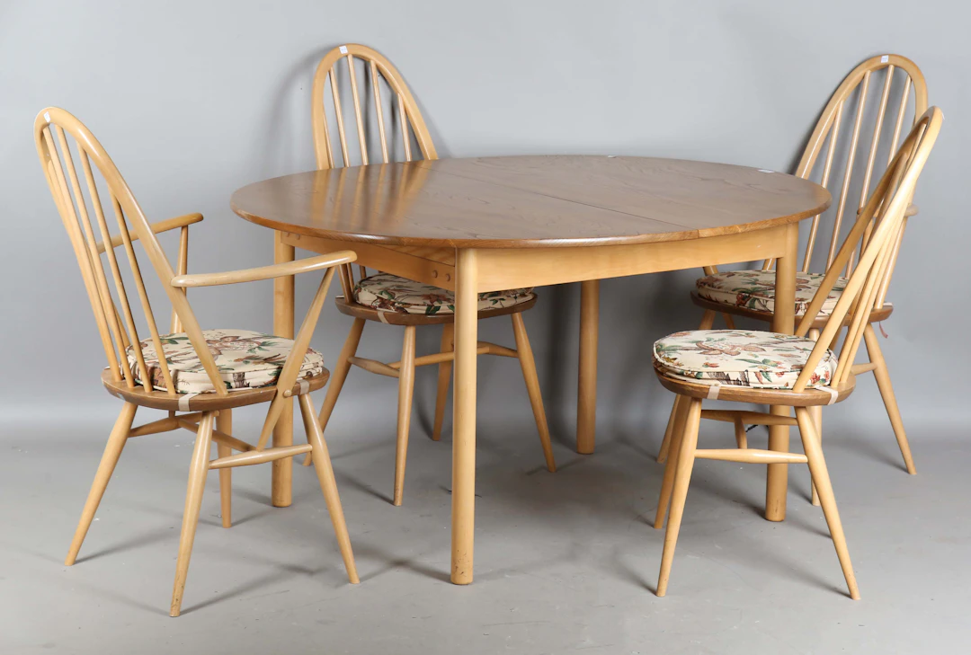 An Ercol elm extending dining table, the oval top with an integral
