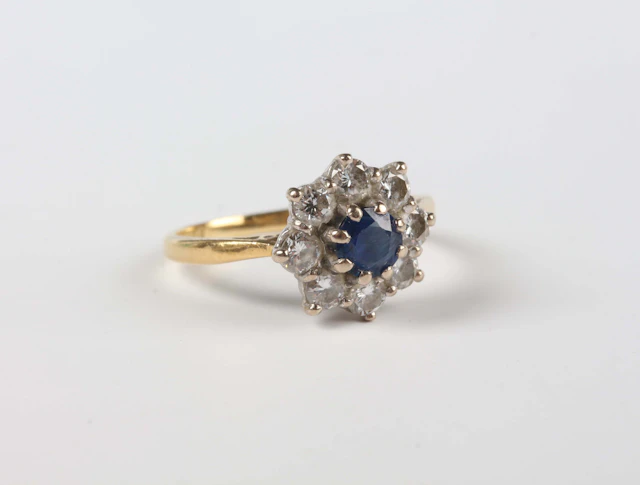 An 18ct gold, sapphire and diamond cluster ring, claw set with the
