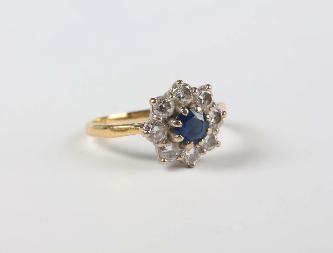 An 18ct gold, sapphire and diamond cluster ring, claw set with the