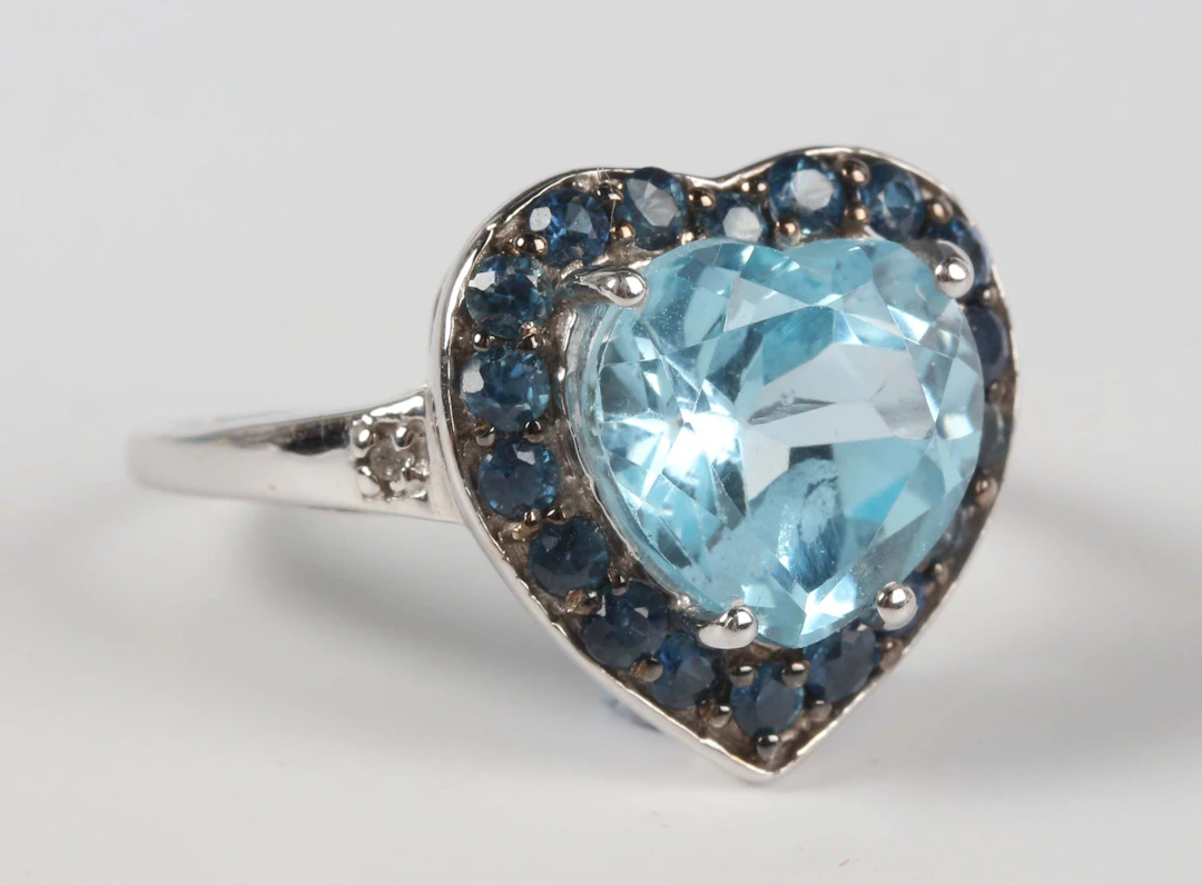 A 9ct white gold, blue topaz and sapphire ring, claw set with a heart