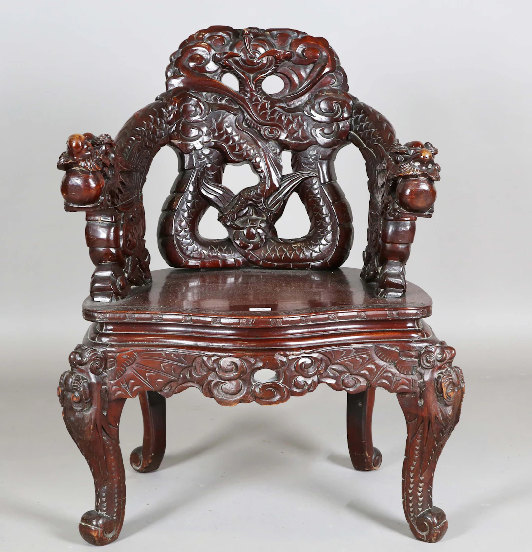 A Japanese carved and stained softwood tub back armchair, profusely