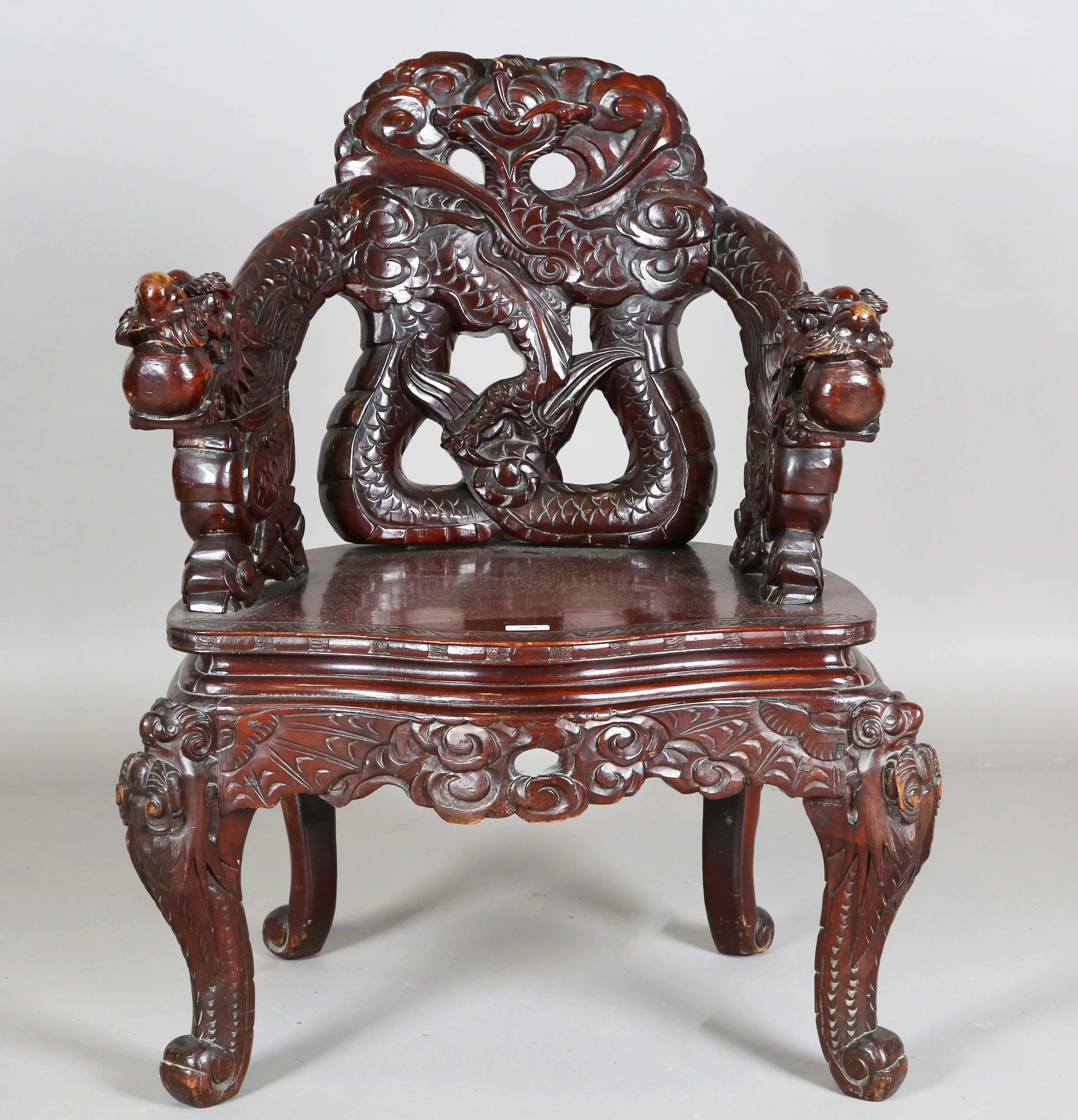 A Japanese carved and stained softwood tub back armchair, profusely