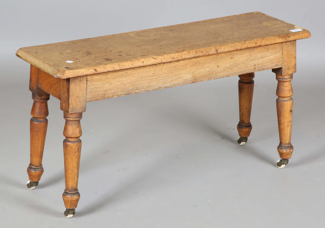 A mid-Victorian faded mahogany bench, raised on turned legs and china