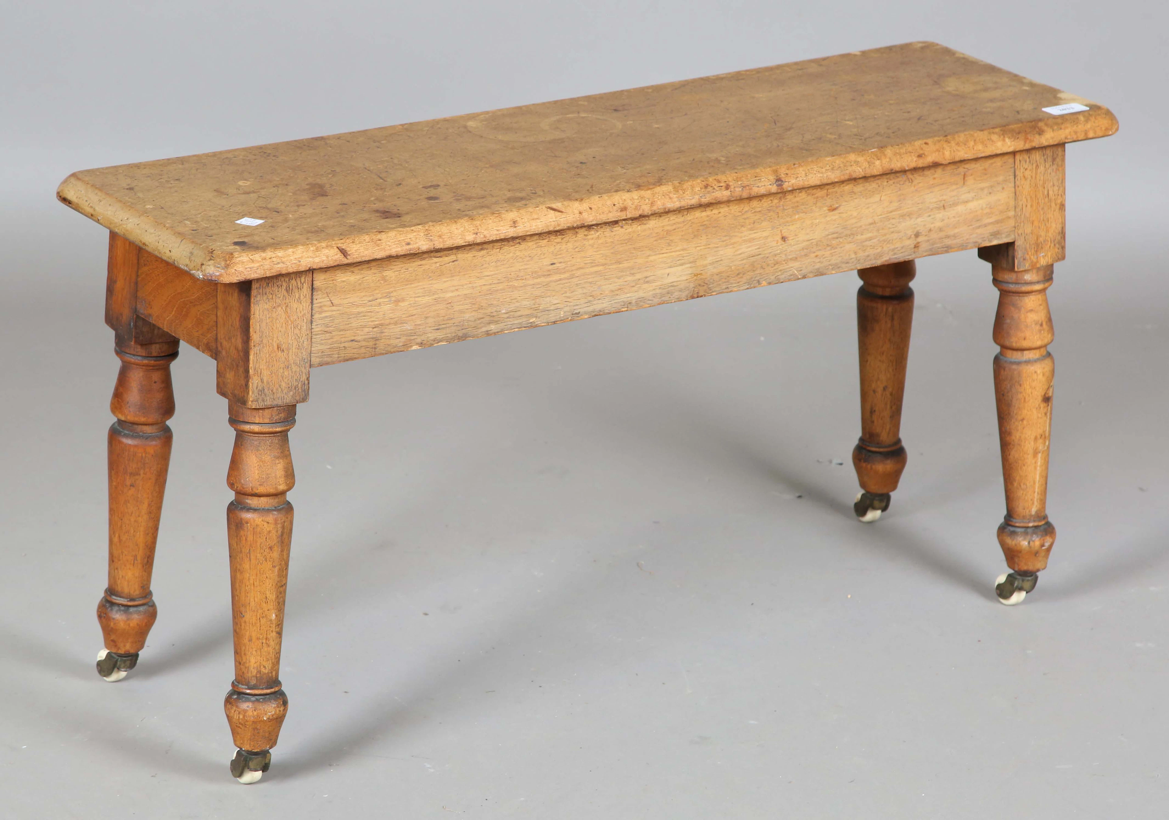 A mid-Victorian faded mahogany bench, raised on turned legs and china