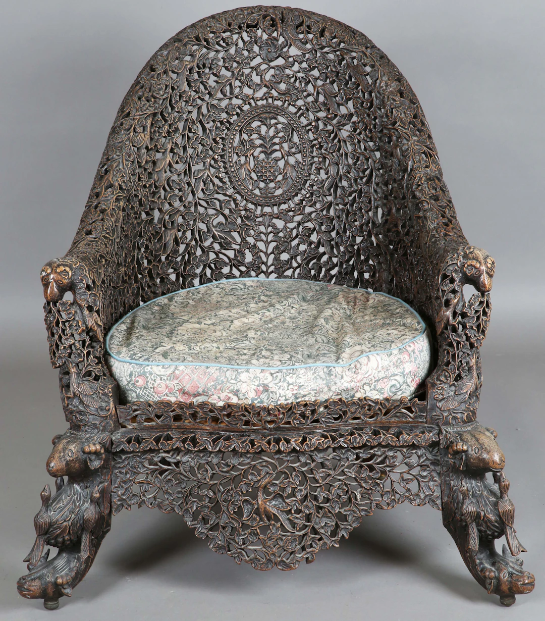 A 19th century Burmese carved and pierced hardwood tub back armchair