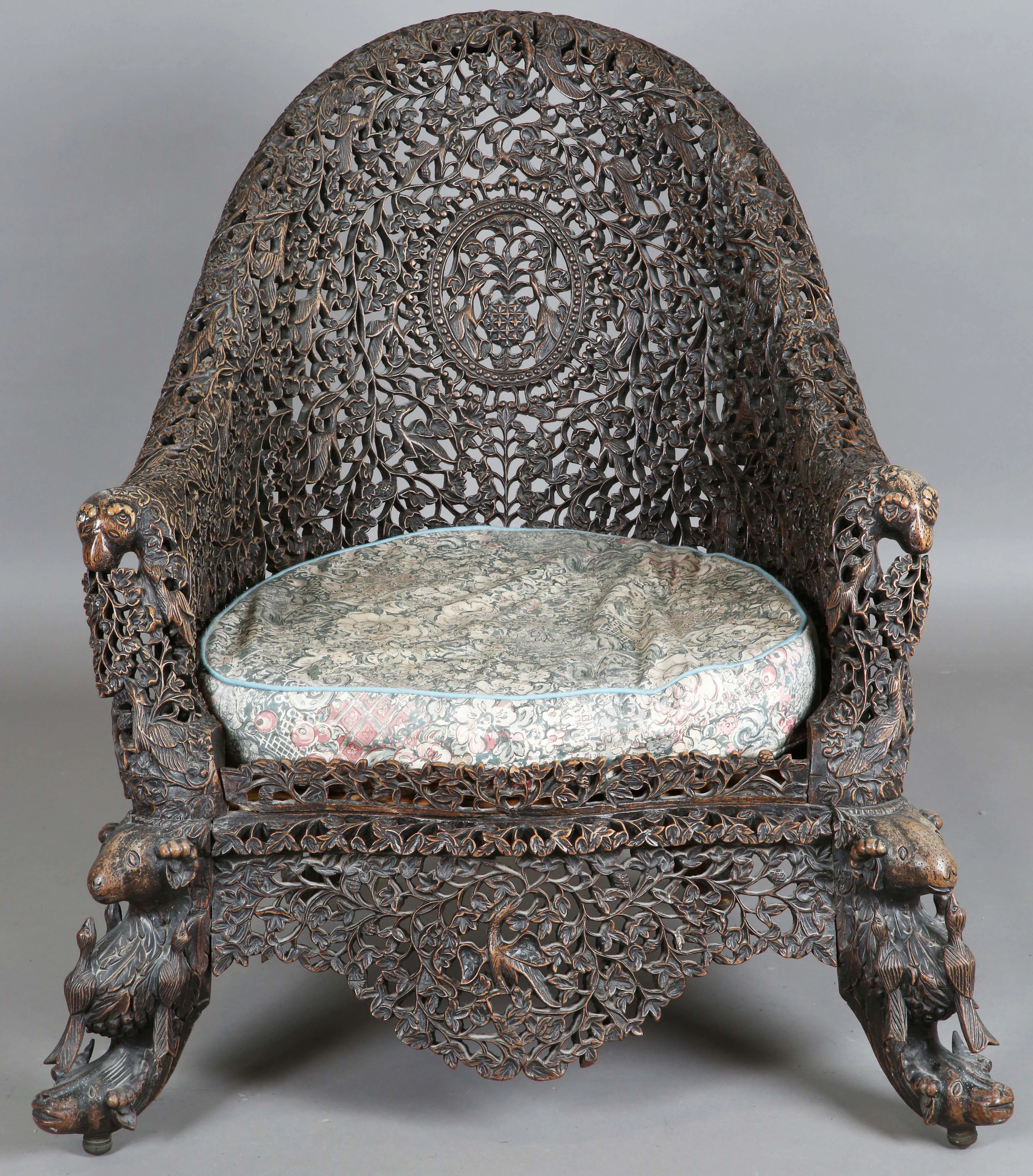 A 19th century Burmese carved and pierced hardwood tub back armchair