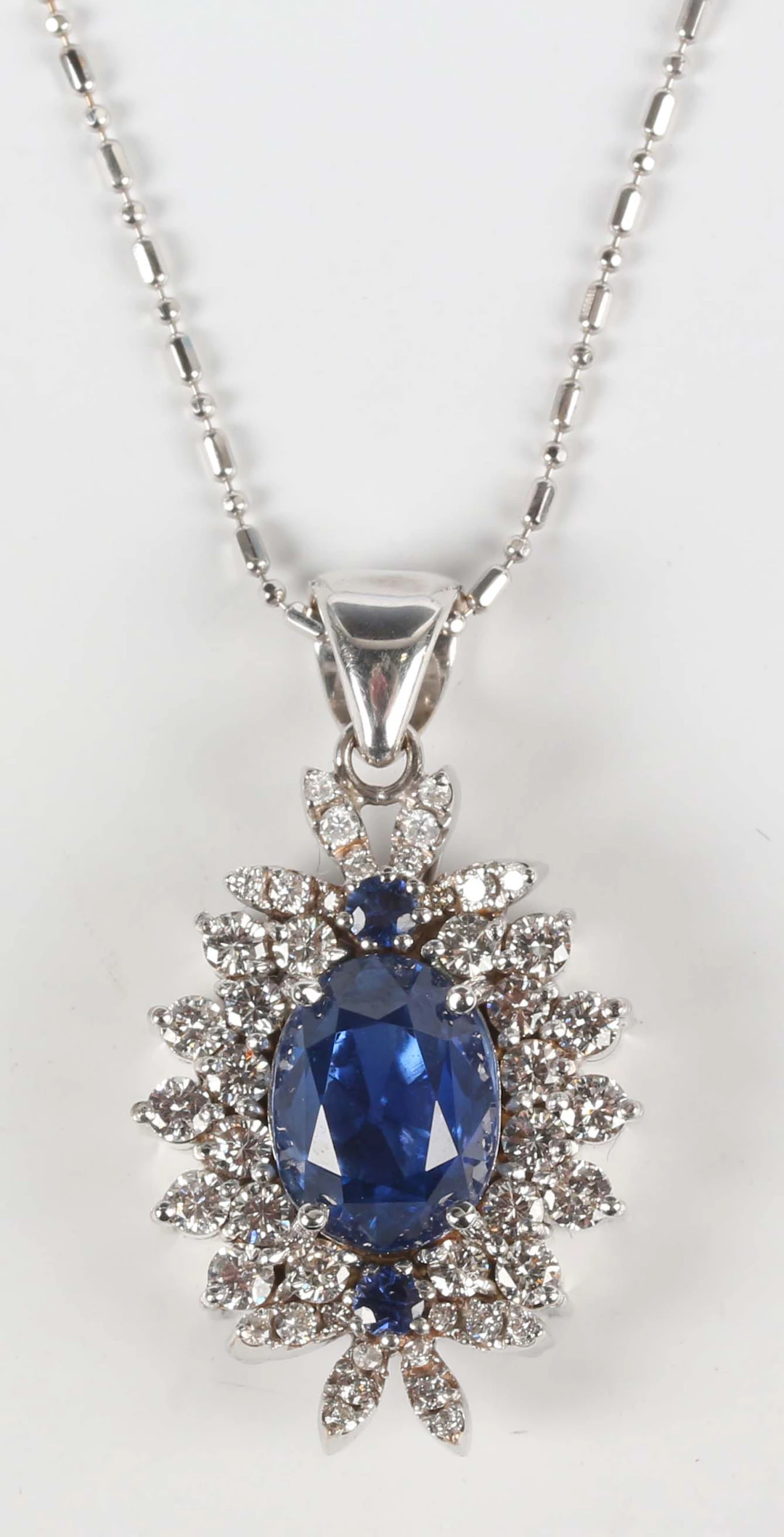 A white gold, sapphire and diamond cluster pendant, claw set with