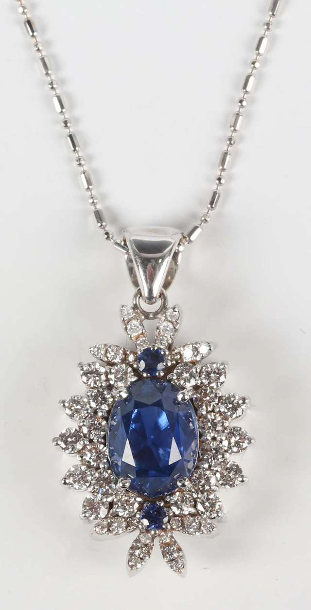 A white gold, sapphire and diamond cluster pendant, claw set with