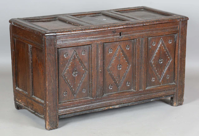 An early 18th century oak panelled coffer, the front with carved lozenge