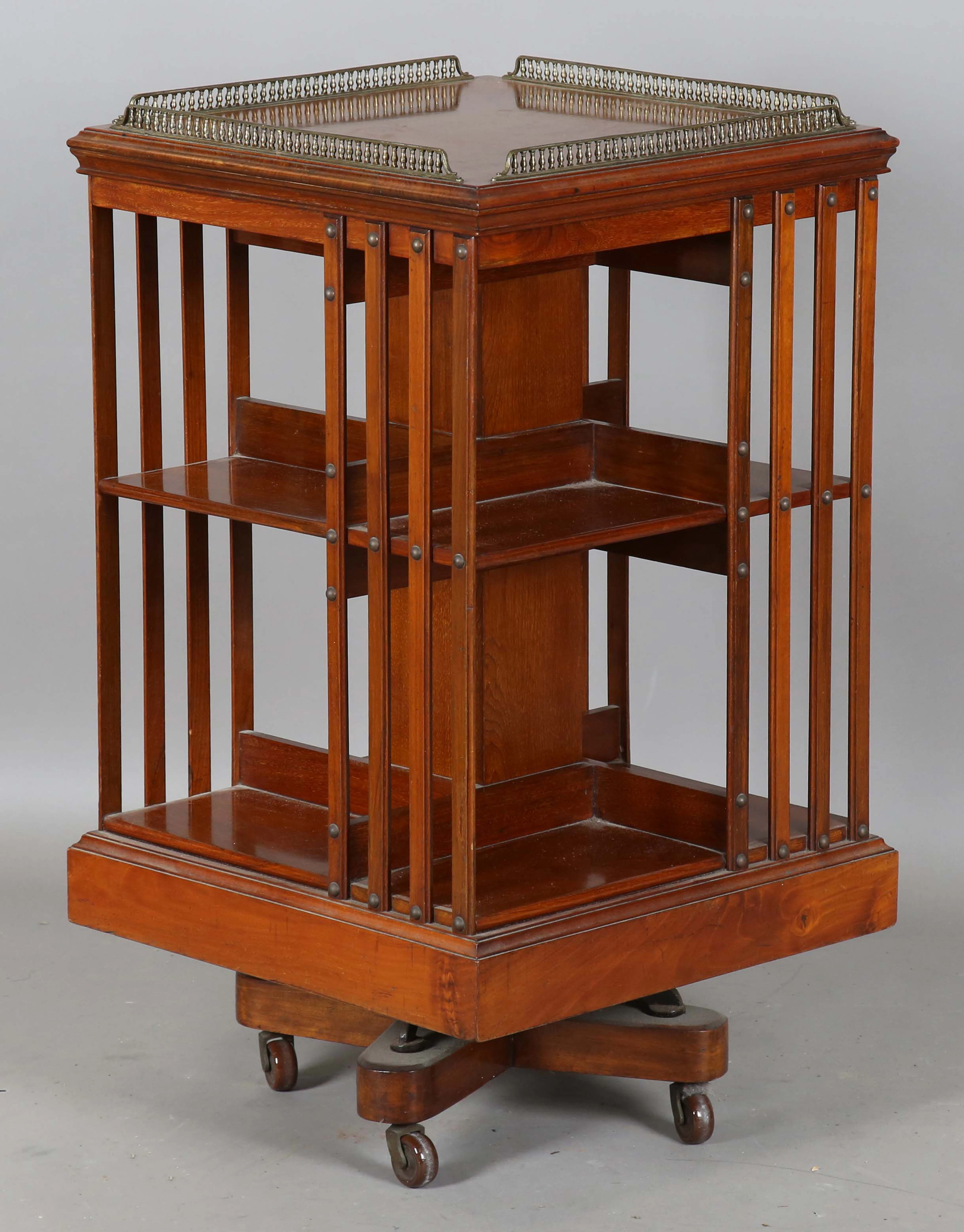 An Edwardian walnut two-tier revolving bookcase with a gilt brass