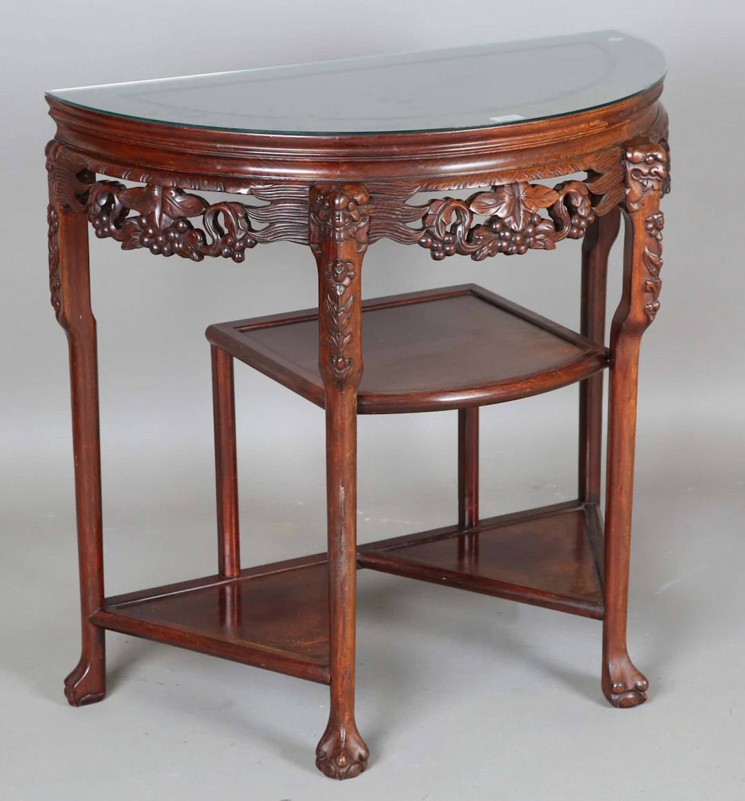 A 20th century Chinese hardwood demi-lune side table with a carved