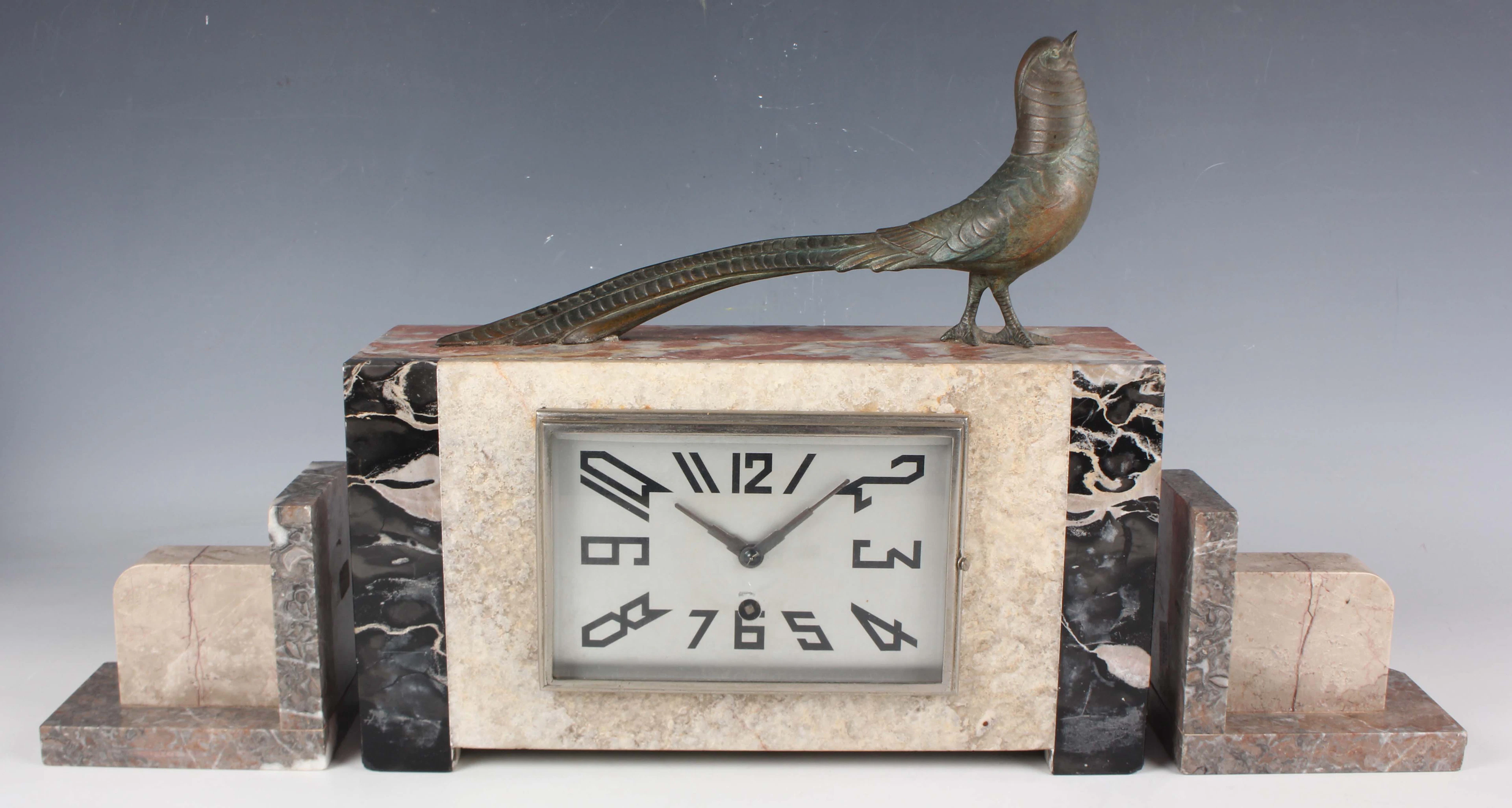 An Art Deco French marble, onyx and spelter mantel clock garniture
