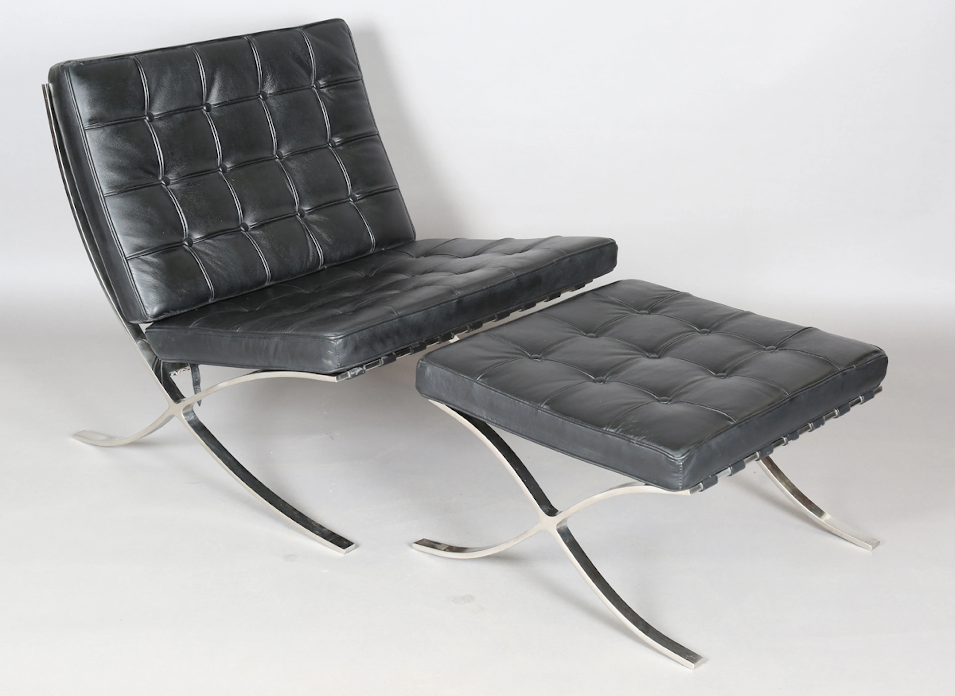 A modern copy of a Barcelona chair and stool, originally designed