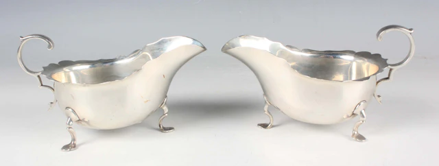 A pair of George V silver sauceboats, each with scroll handle, on