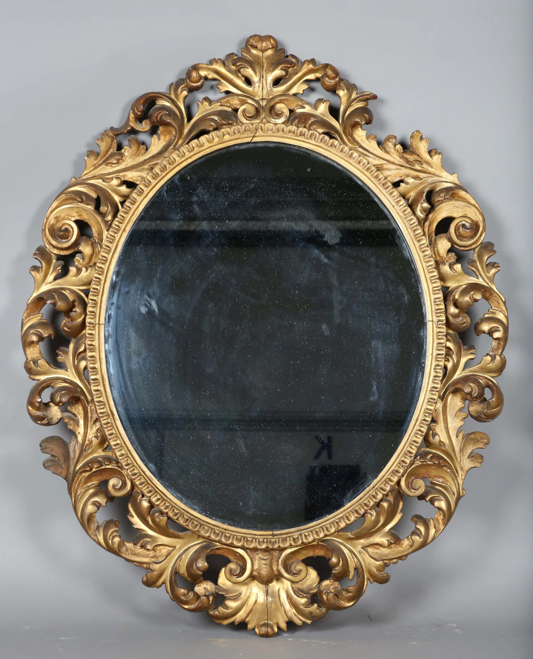An early 20th century Florentine giltwood oval wall mirror, the frame