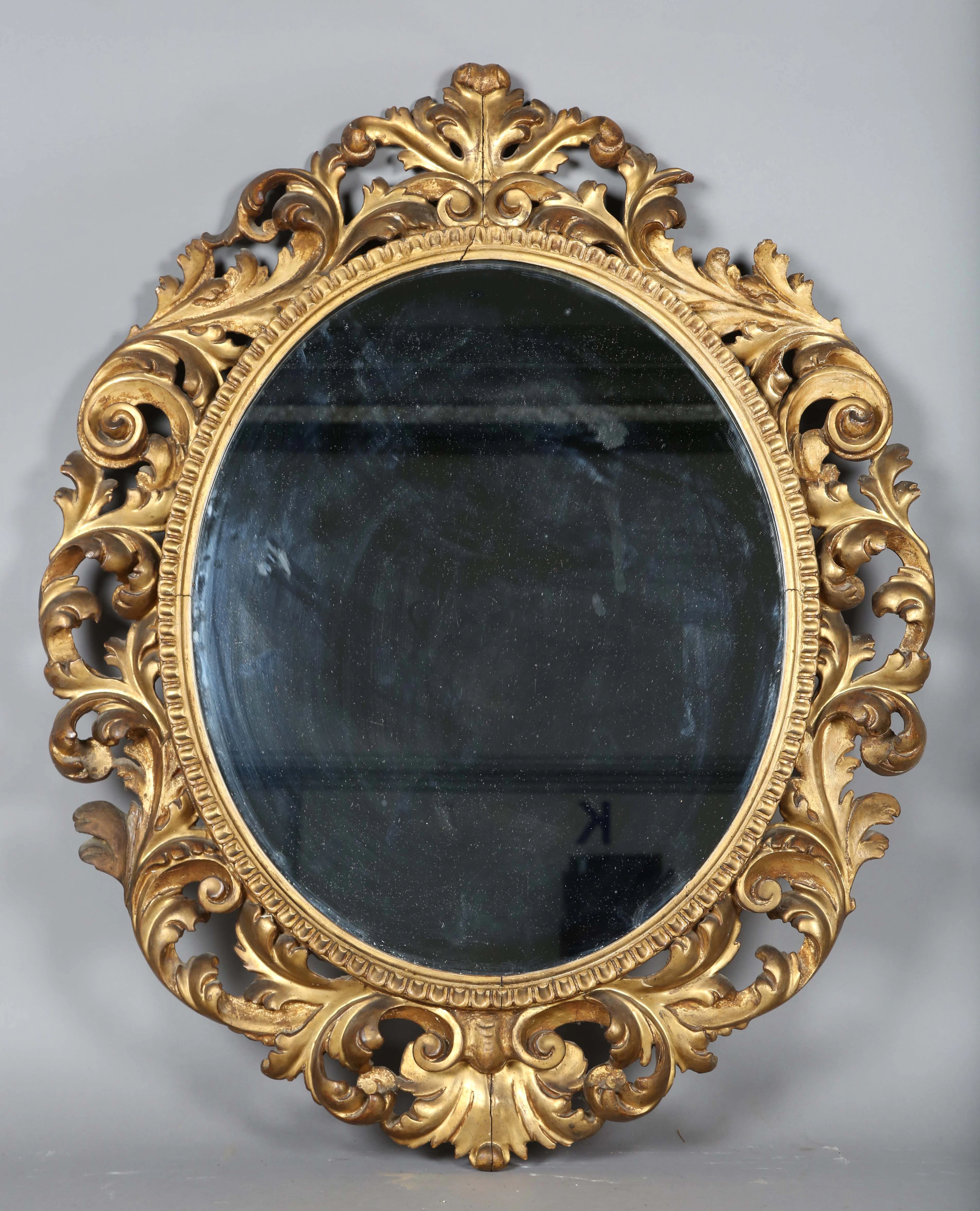 An early 20th century Florentine giltwood oval wall mirror, the frame