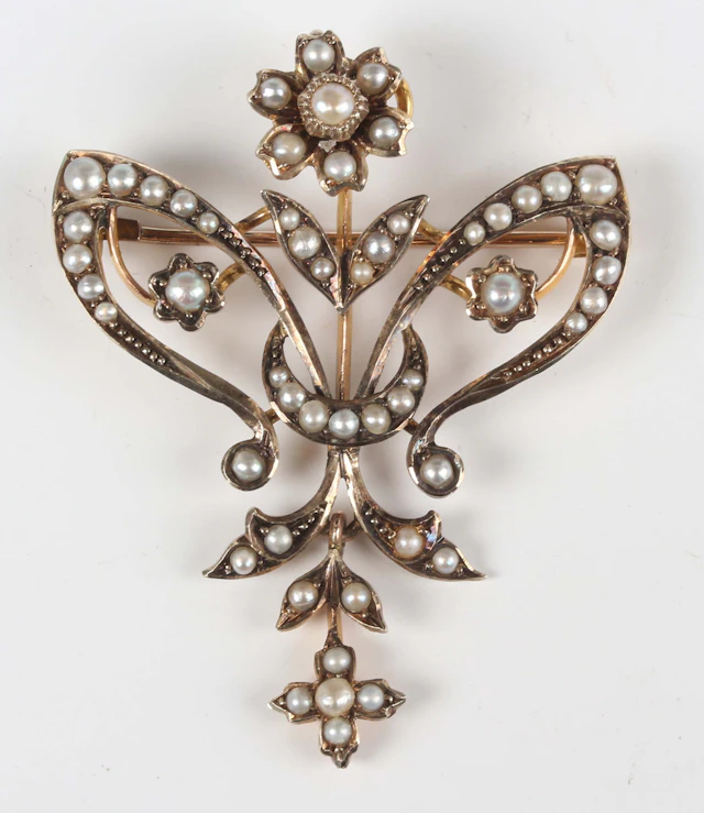An early 20th century gold and seed pearl pendant brooch in an openwork