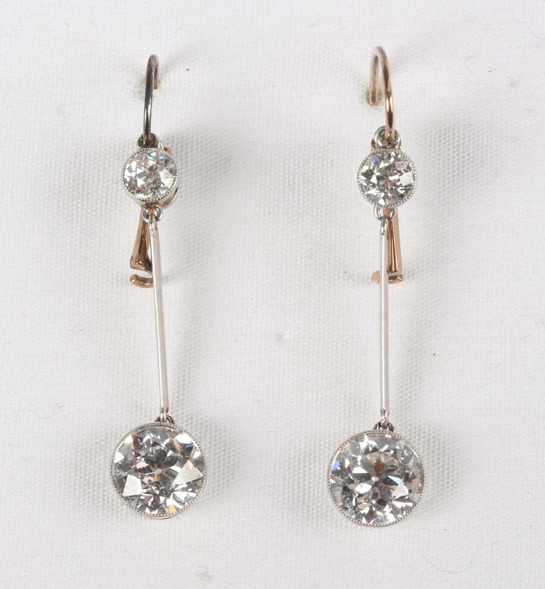 A pair of diamond two stone pendant earrings, each collet set with