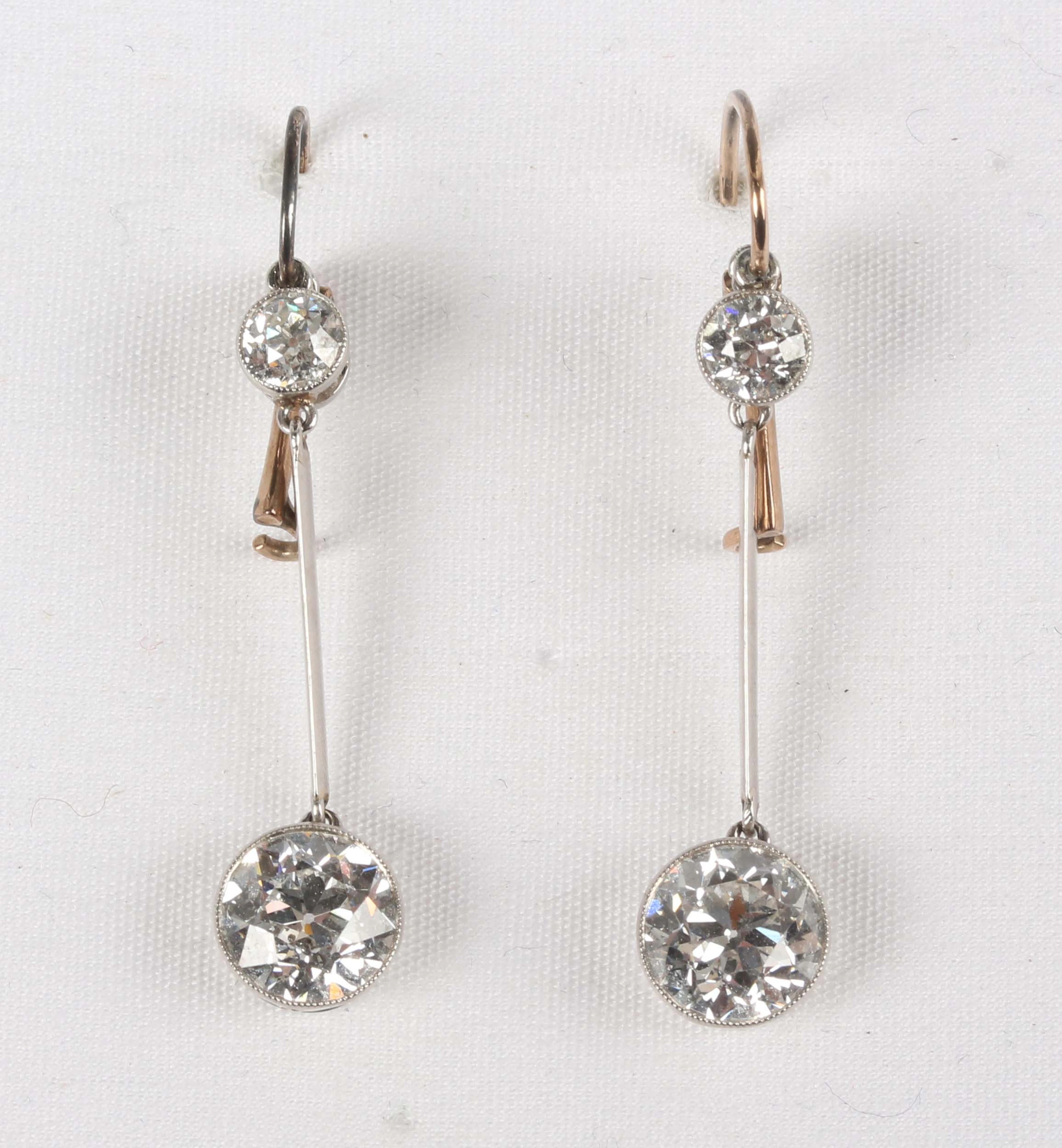 A pair of diamond two stone pendant earrings, each collet set with