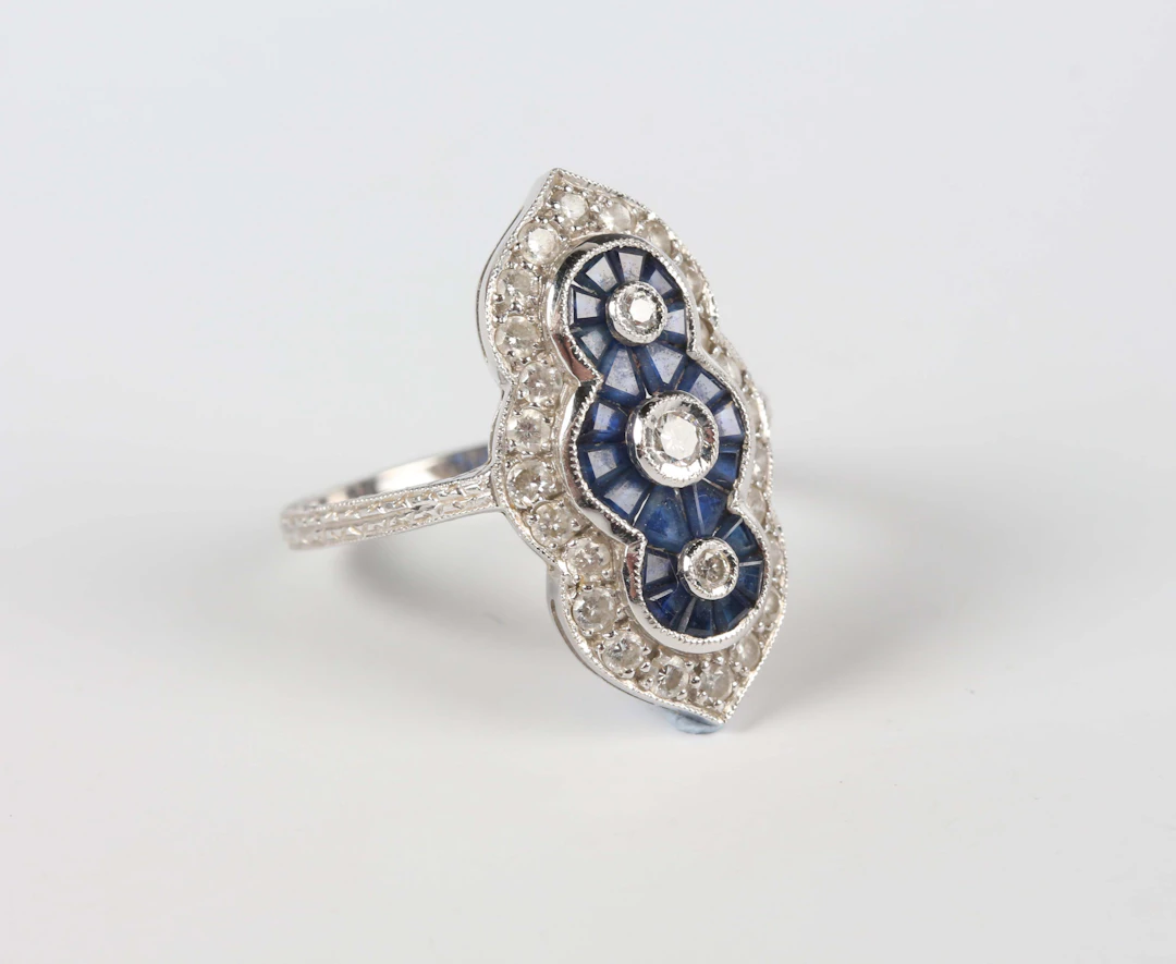A white gold, sapphire and diamond ring in a foliate panel design