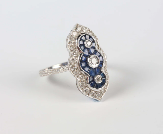 A white gold, sapphire and diamond ring in a foliate panel design