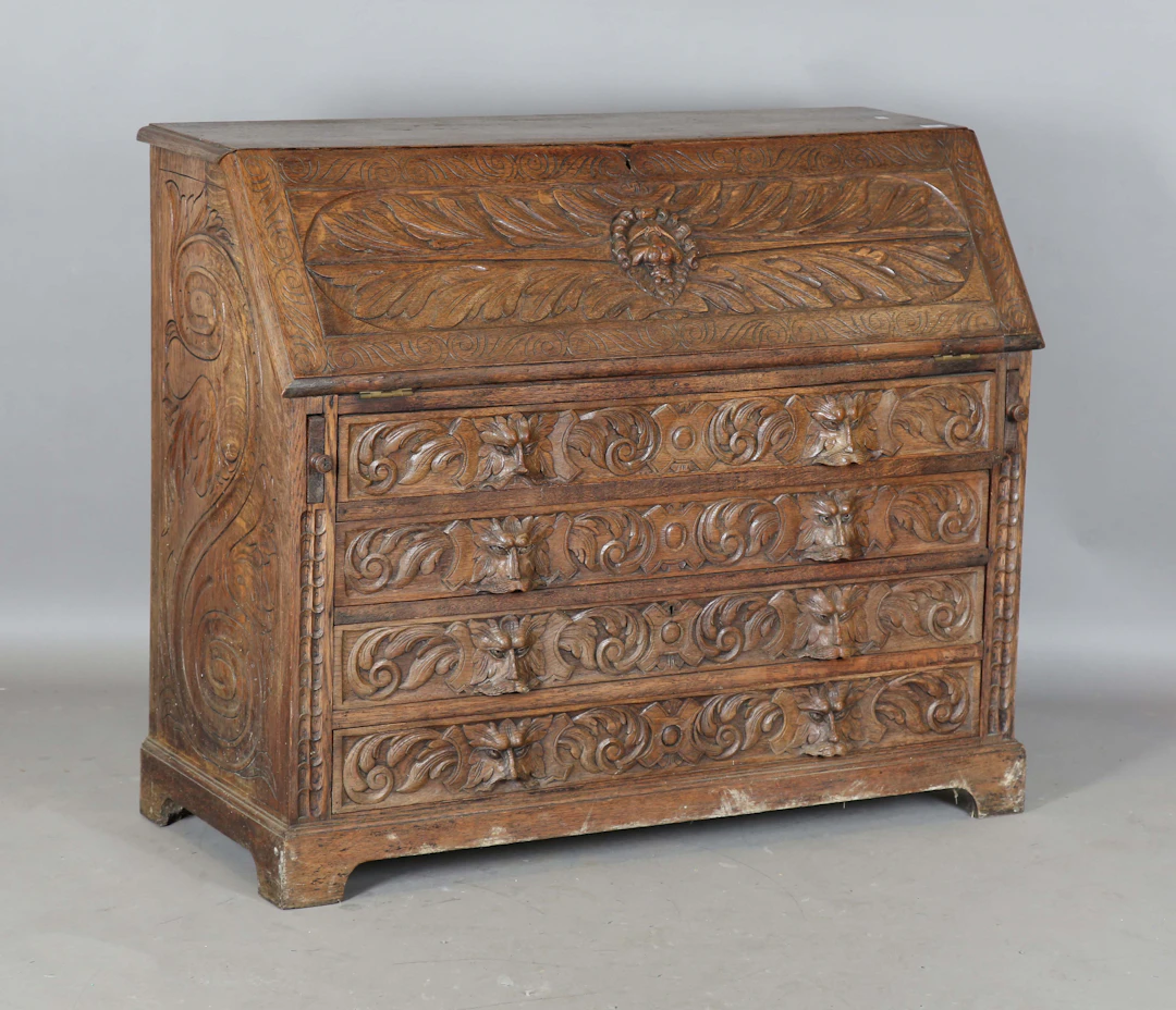 A late Victorian carved oak bureau, the fall flap and four drawers