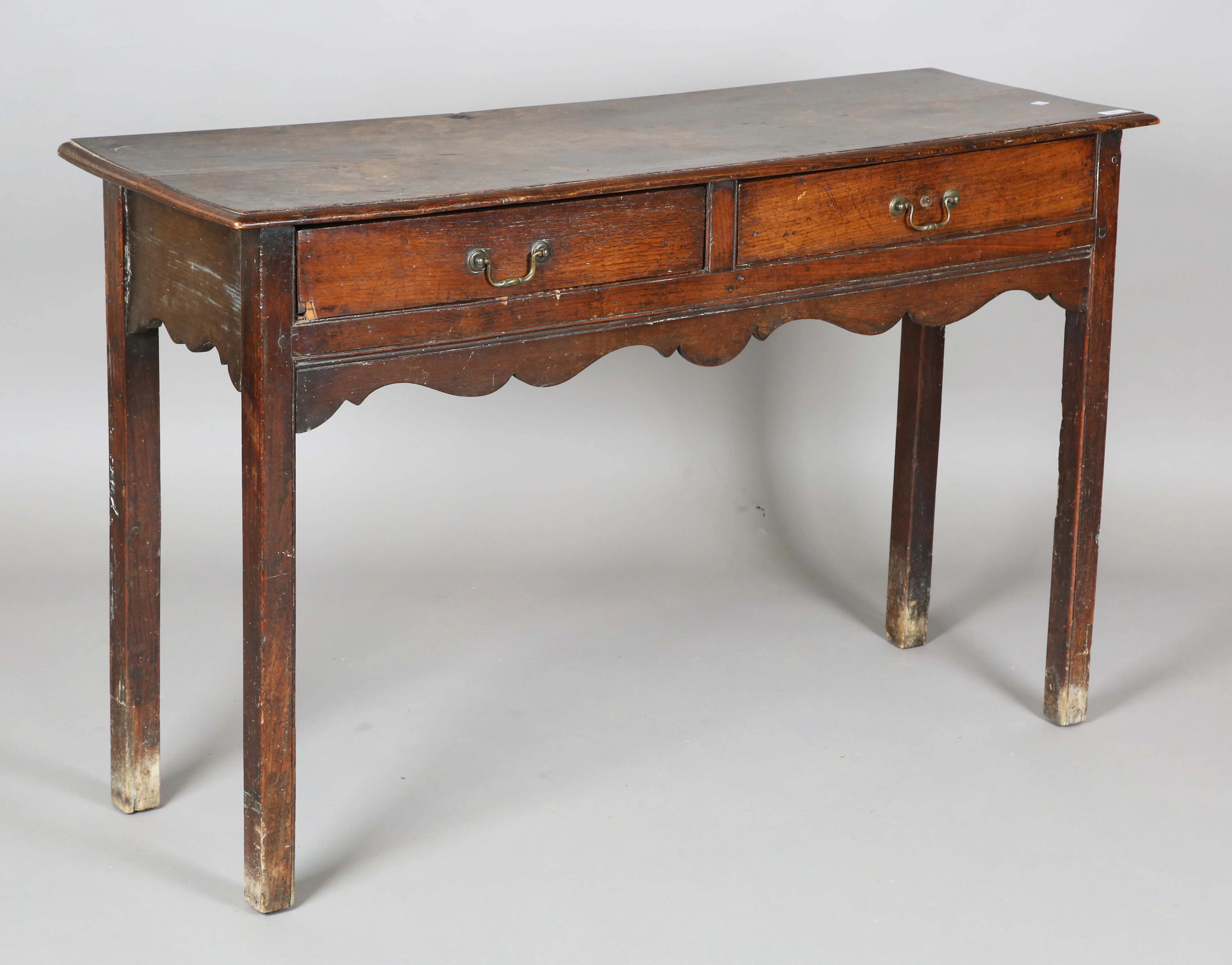 A George III provincial oak side table, fitted with two drawers, on