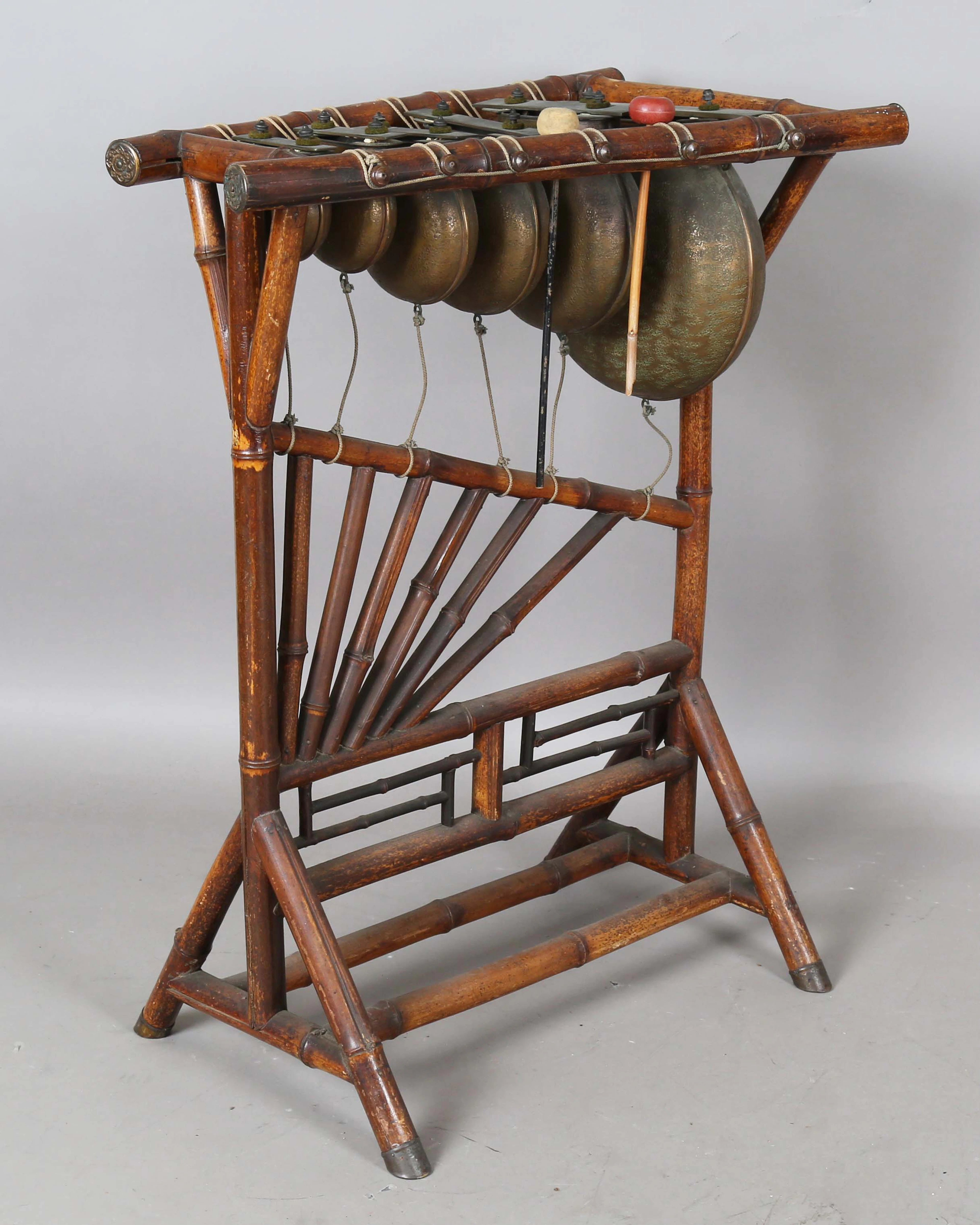 An early 20th century glockenspiel, raised on a bamboo stand, width 64cm.