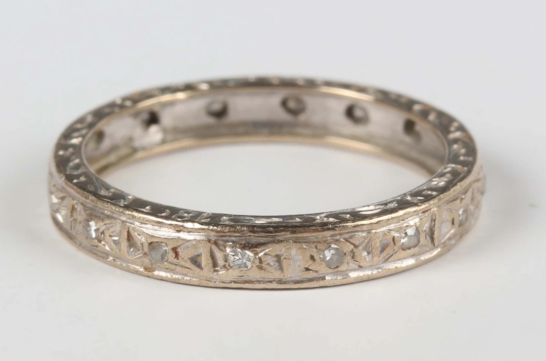 A white gold and diamond eternity ring with engraved decoration, mounted