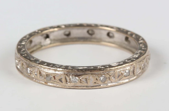 A white gold and diamond eternity ring with engraved decoration, mounted