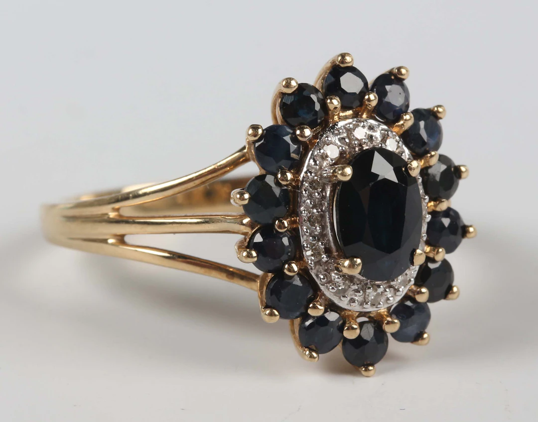 A 9ct gold, sapphire and diamond oval cluster ring, claw set with