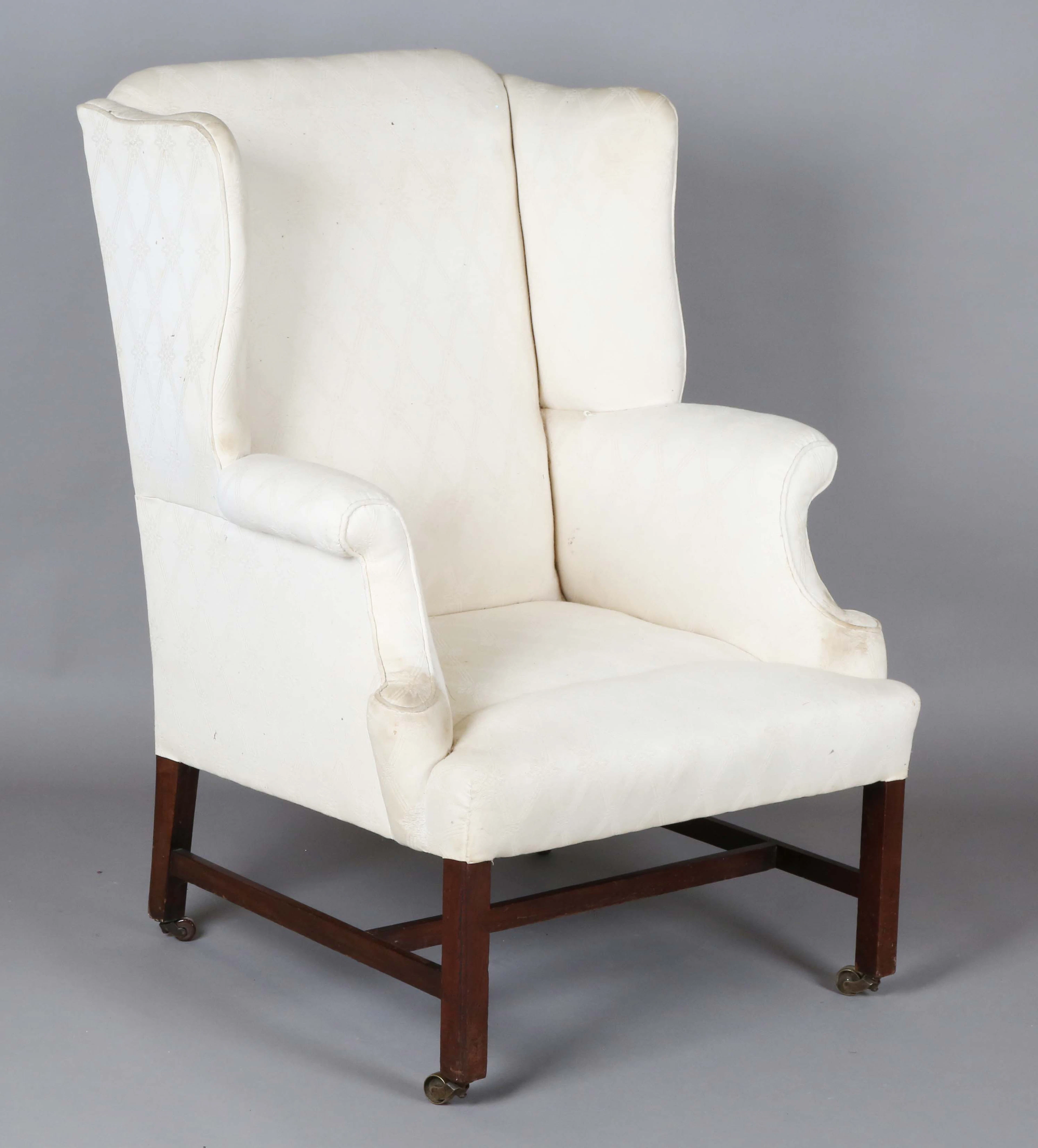 A 19th century George III style wing back armchair, on mahogany block