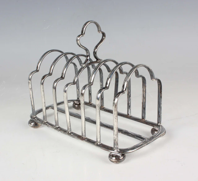 A George V silver six-division toast rack with central handle and