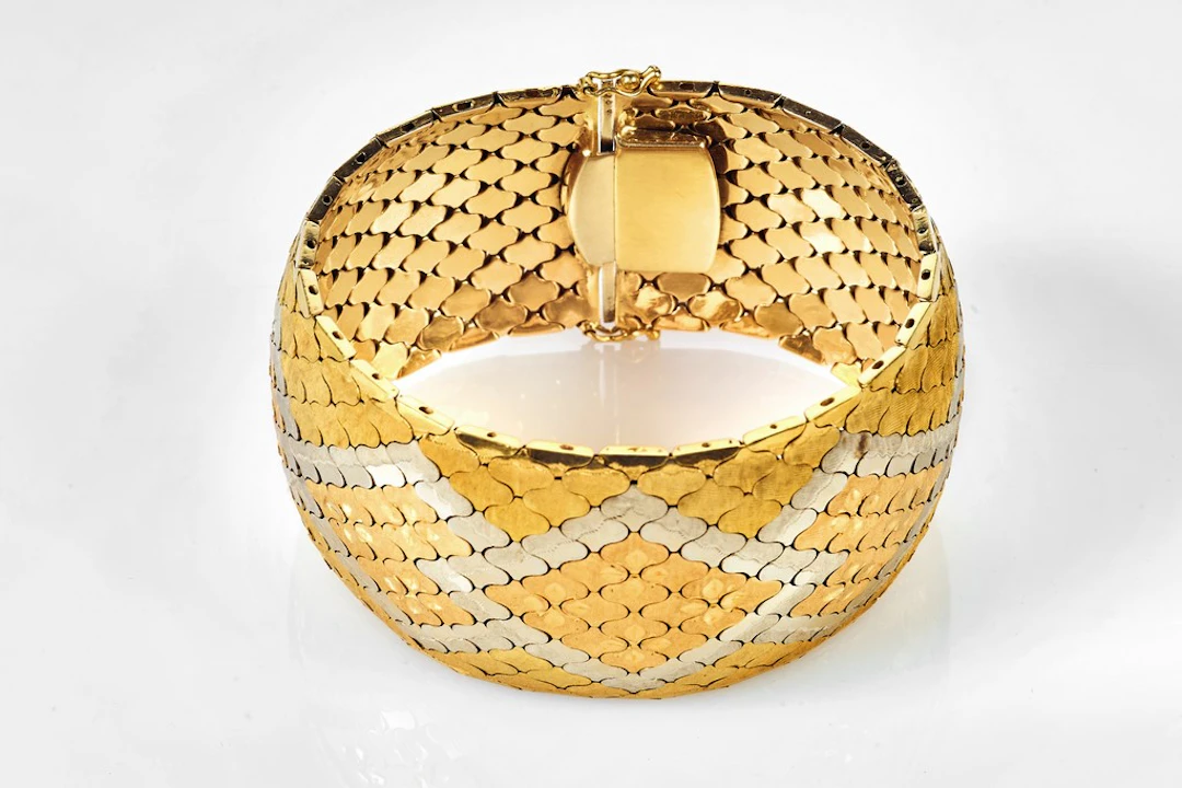 Bracelet ruban souple en trois ors à décor de chevrons et trèfles.