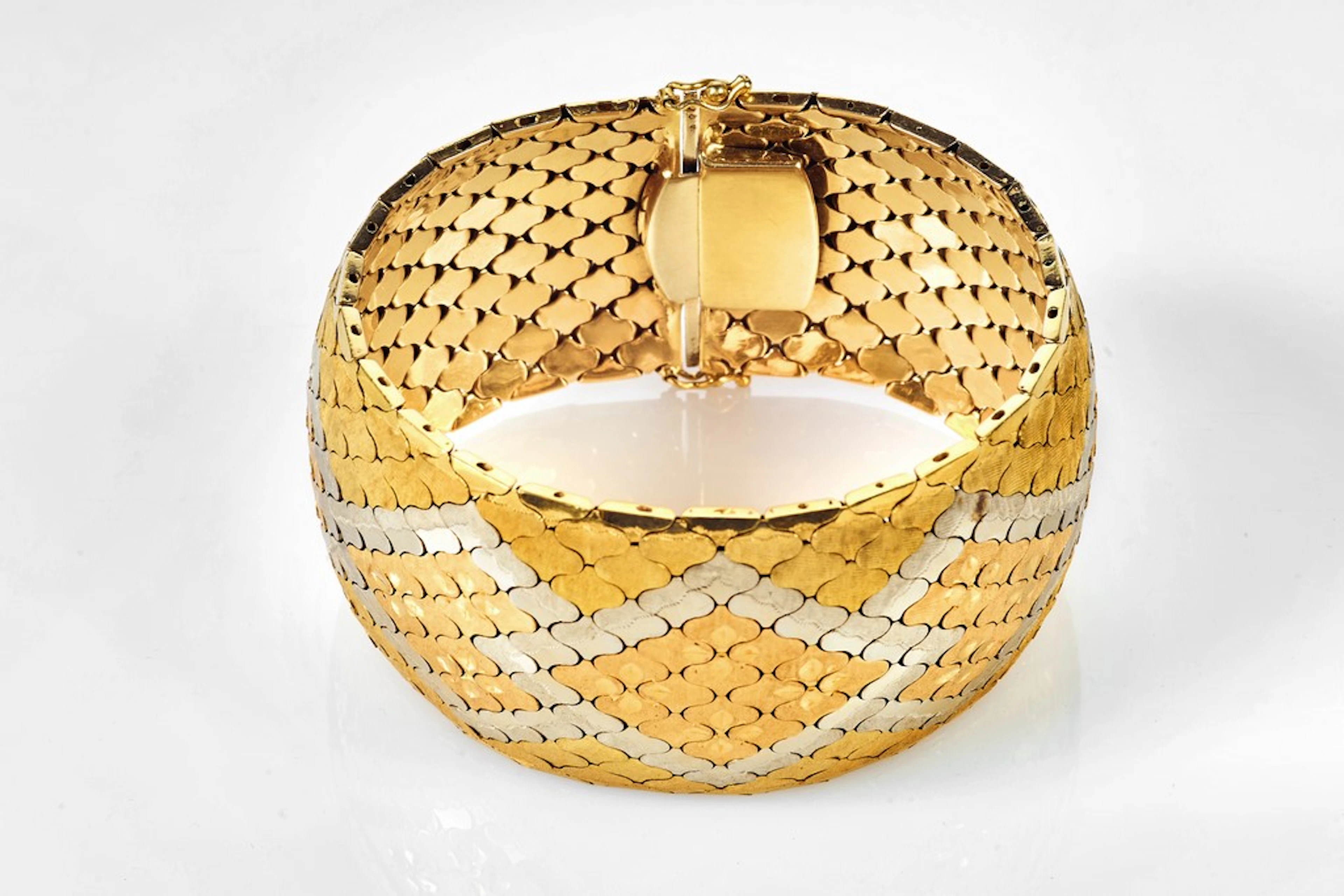 Bracelet ruban souple en trois ors à décor de chevrons et trèfles.