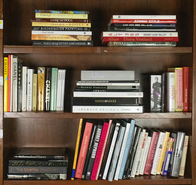Three shelves of hardcover books pertaining to fashion brands and