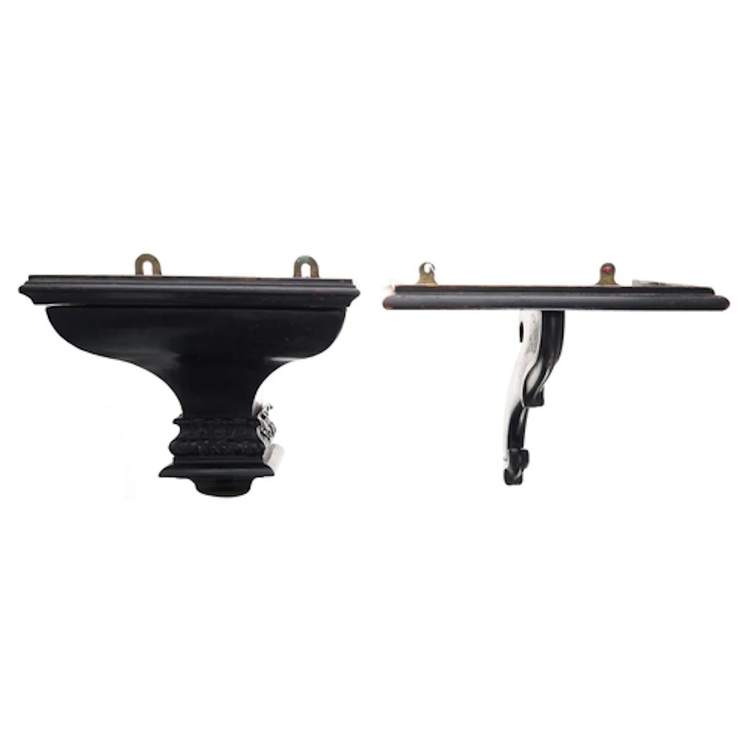 Two ebonised clock brackets, one with ogee and foliate carve...