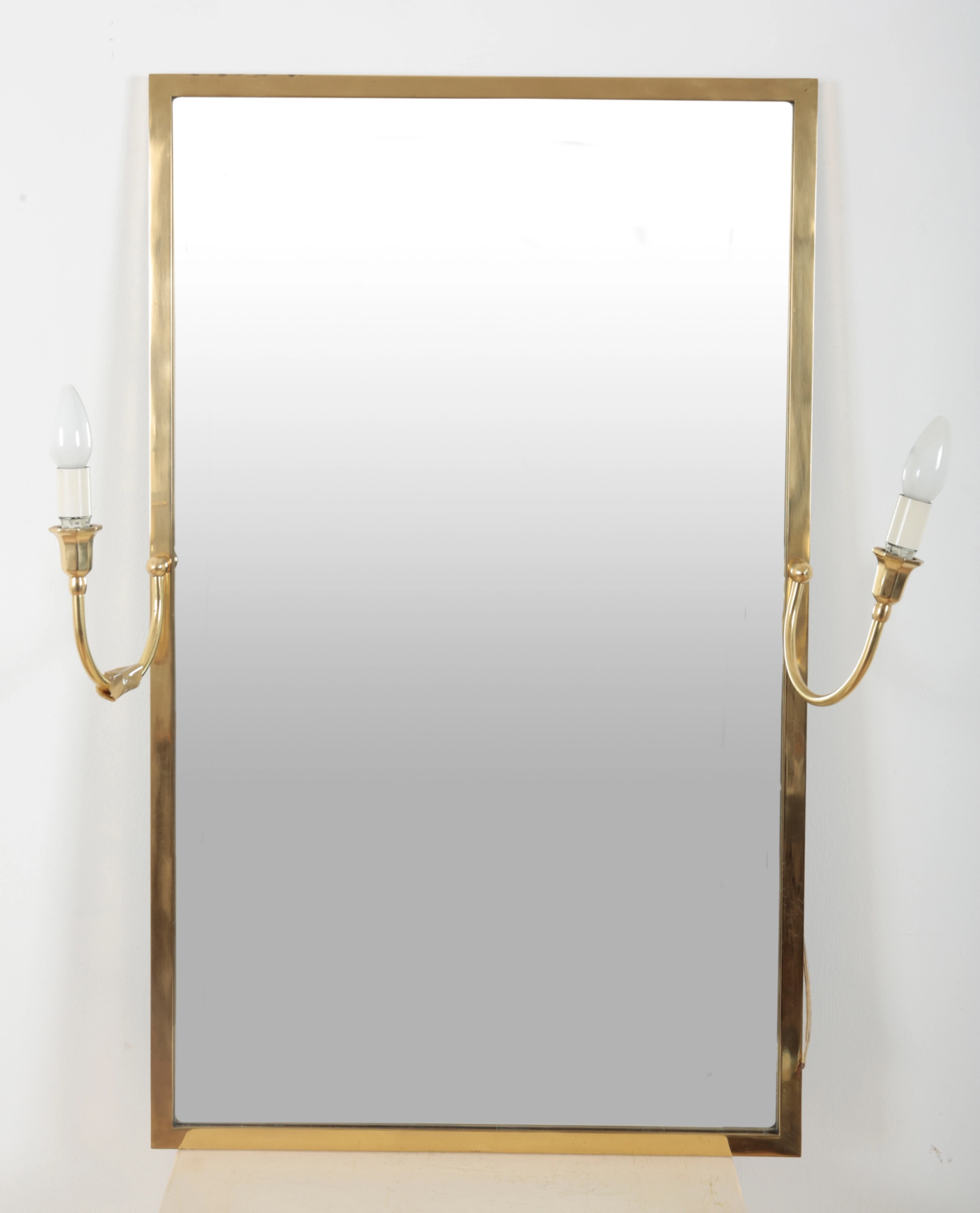 A RECTANGULAR BRASS MIRROR WITH ELECTRIFIED CANDLE SCONCES