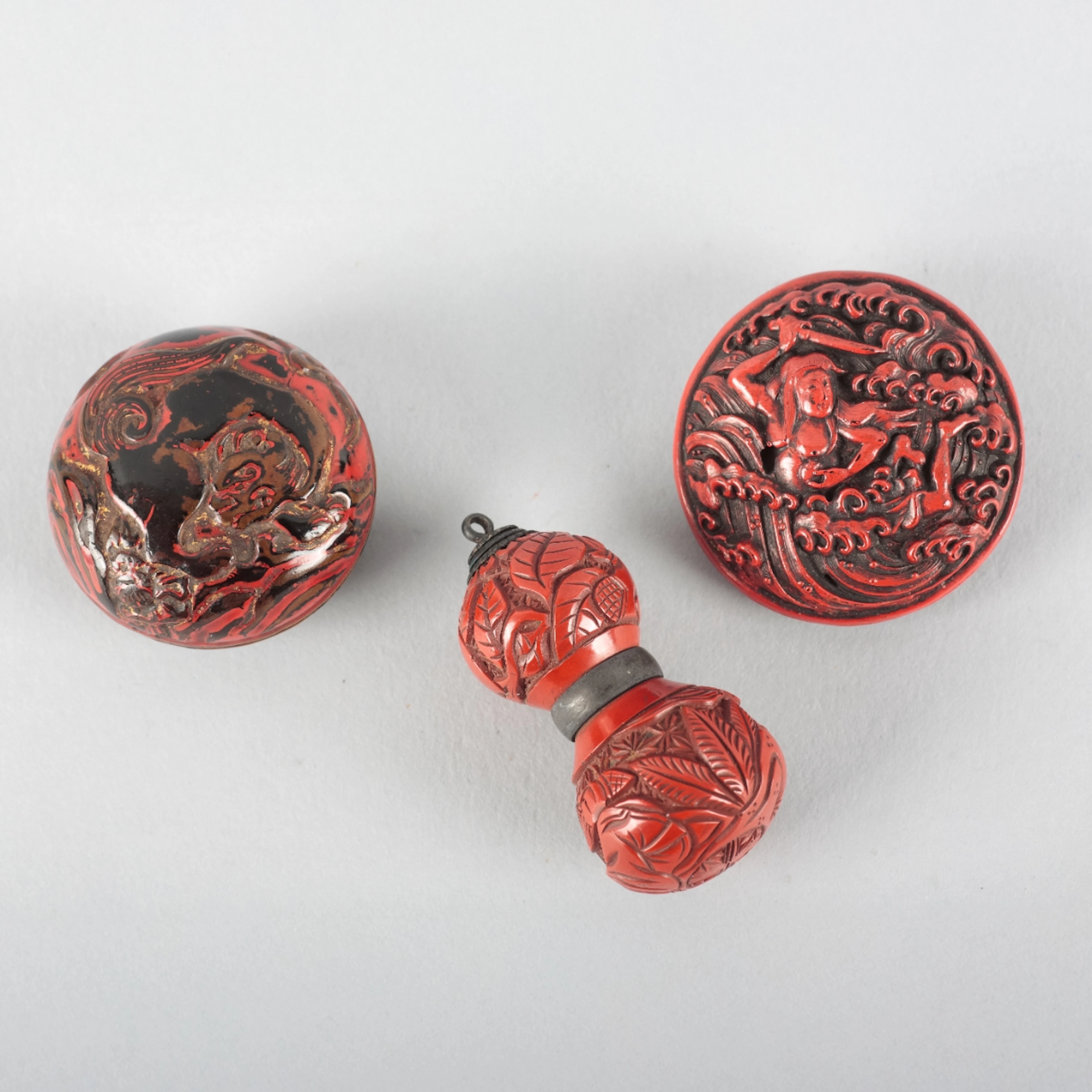 TWO SIMILAR JAPANESE RED LACQUERED MANJU NETSUKES