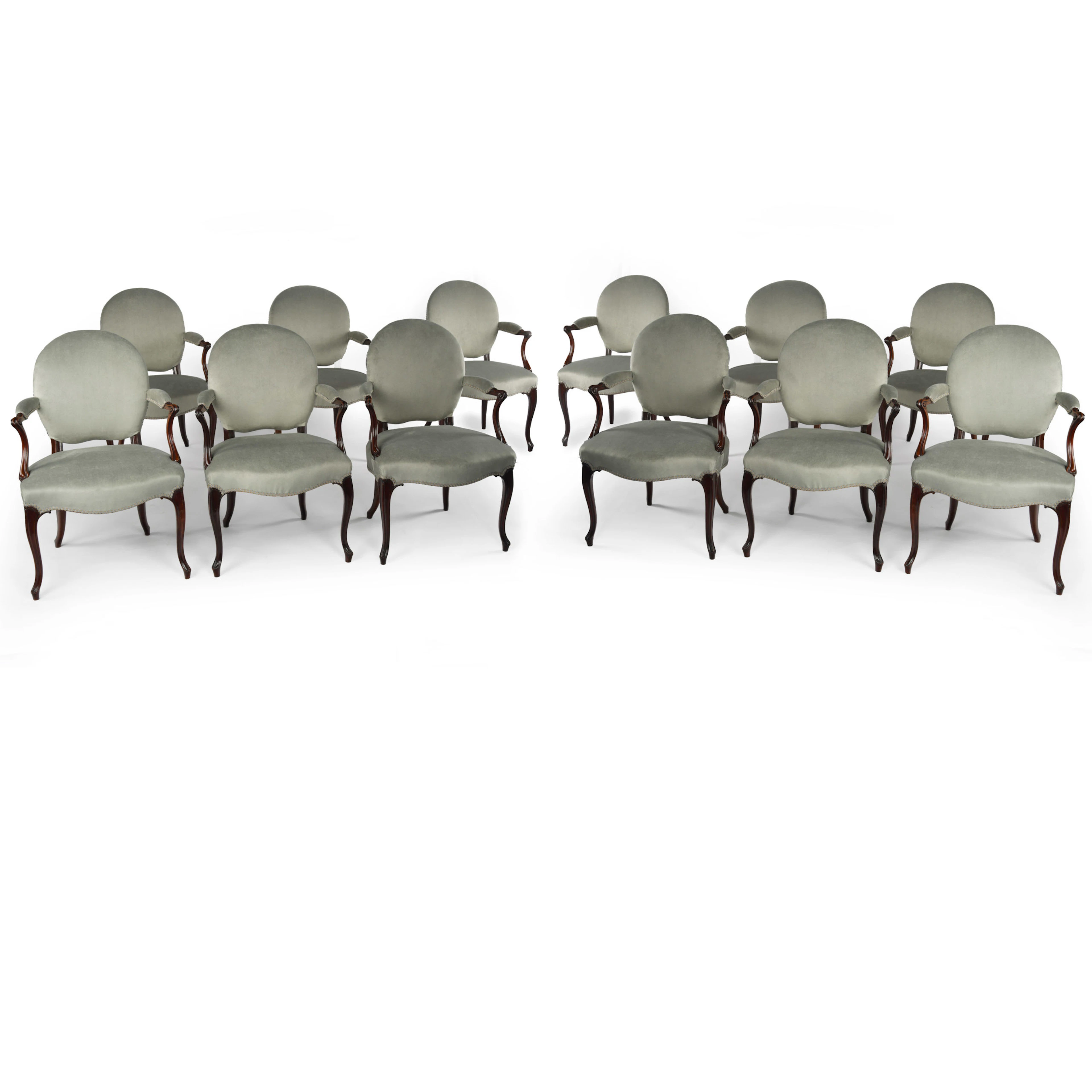 A rare set of twelve George III mahogany open arm chairs in the French