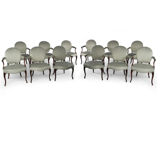 A rare set of twelve George III mahogany open arm chairs in the French