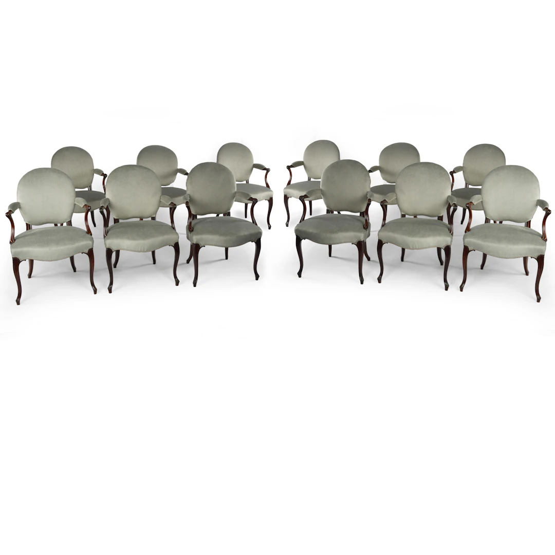 A rare set of twelve George III mahogany open arm chairs in the French