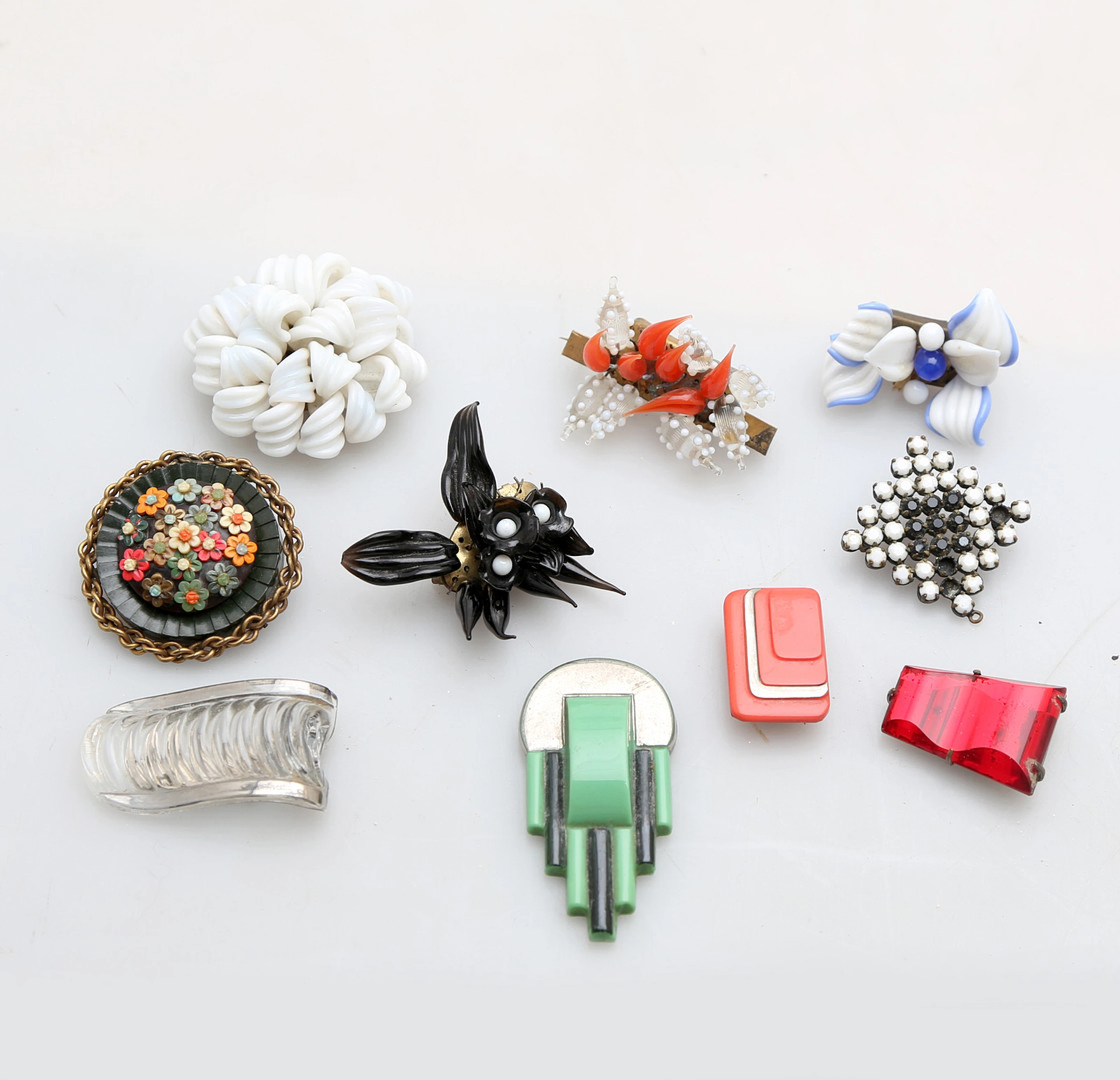 Ten brooches in coloured glass and various materials, circa 1960.