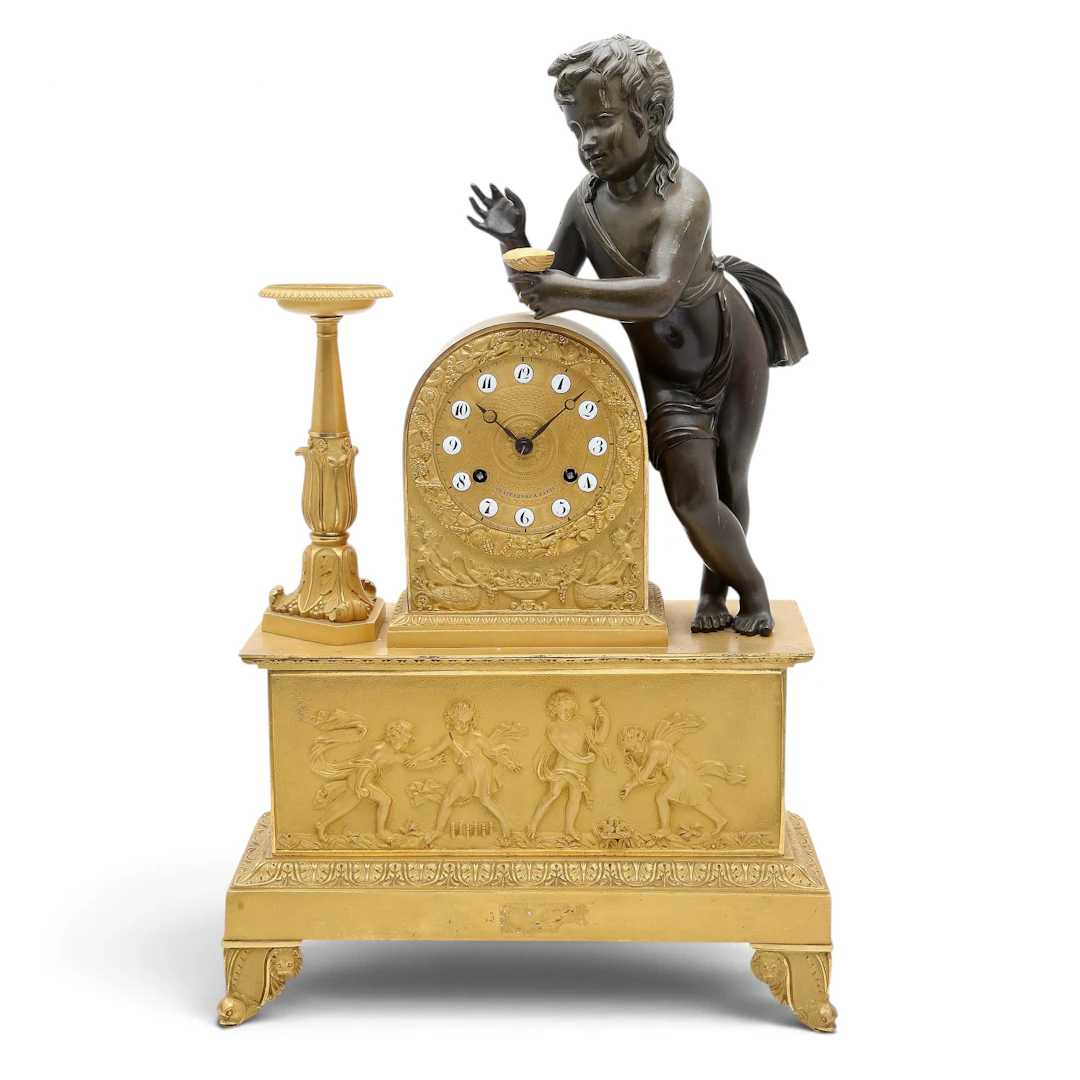 French Charles X mantel clock centered by a classical child in gilt