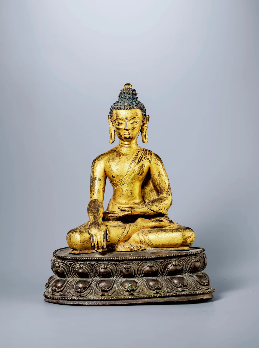 A GILT-BRONZE SEATED FIGURE OF SHAKYAMUNI, 15TH CENTURY
