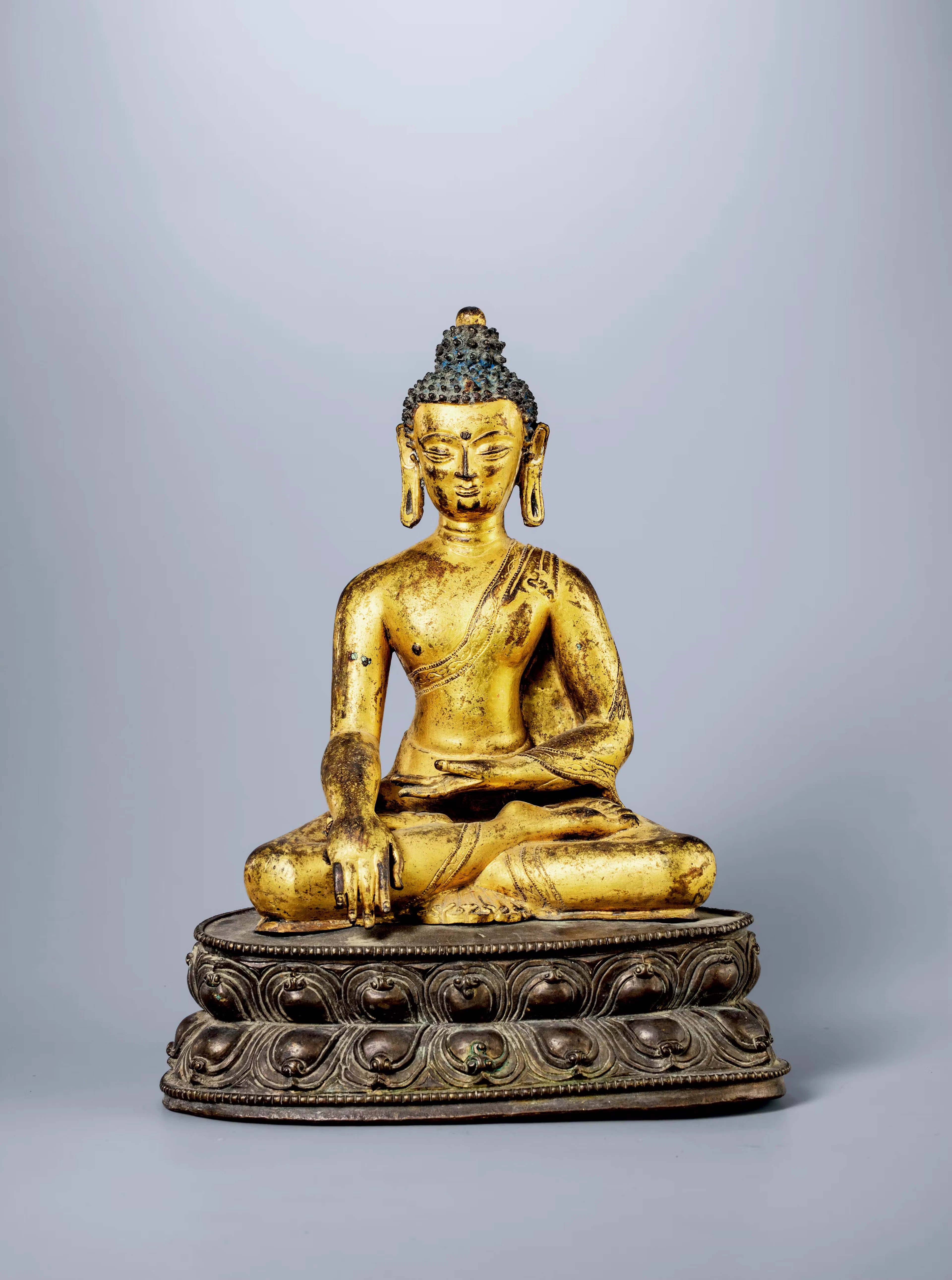 A GILT-BRONZE SEATED FIGURE OF SHAKYAMUNI, 15TH CENTURY