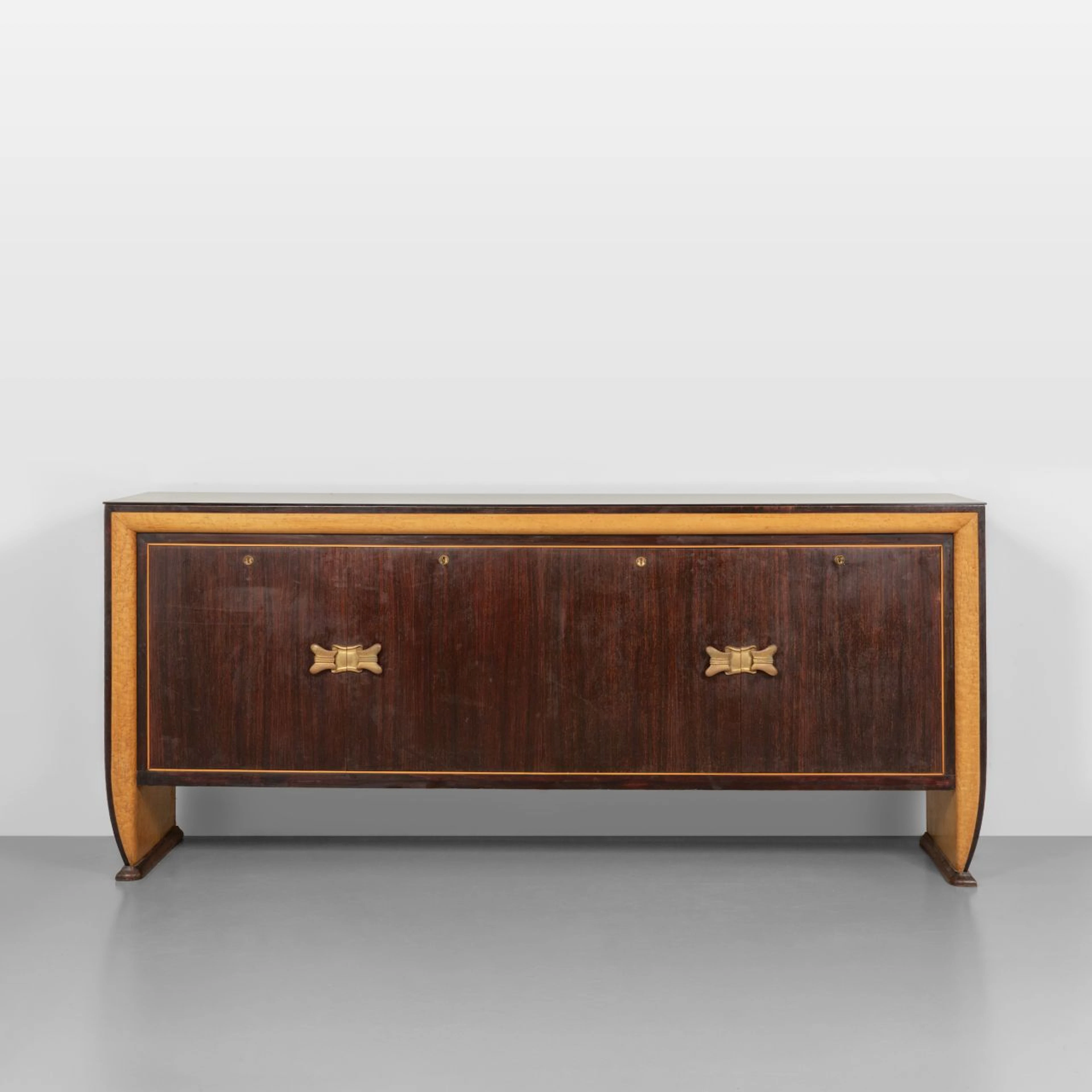 UNA CREDENZA, anni '40. Varie essenze di legno, piano in vetro opale